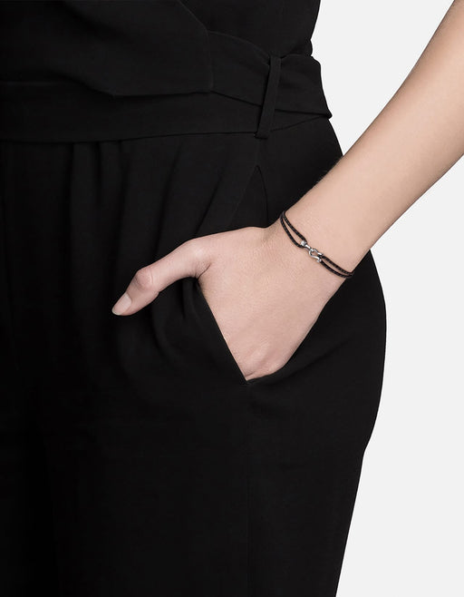 Miansai polished silver tone screw cuff on a black bungee bracelet with brown tracers worn on the wrist