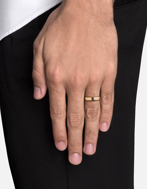 Miansai gold vermeil ring with an upright blue sapphire baguette set flush at the front, worn on a finger