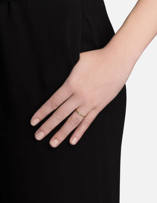 Miansai gold vermeil heart ring with a small heart-cut sapphire worn low on a finger against black clothing