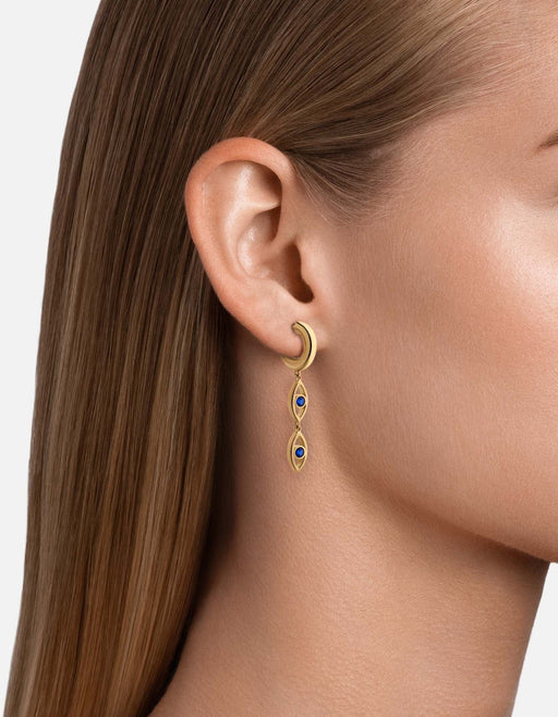 Miansai gold vermeil hoop earring with two dangling open evil eye charms centered with blue spinels worn on an ear