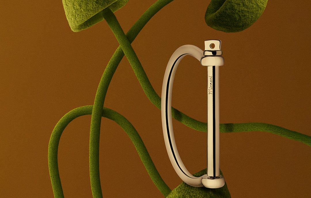 Women's gold screw cuff bracelet on brown background with felt mushrooms.