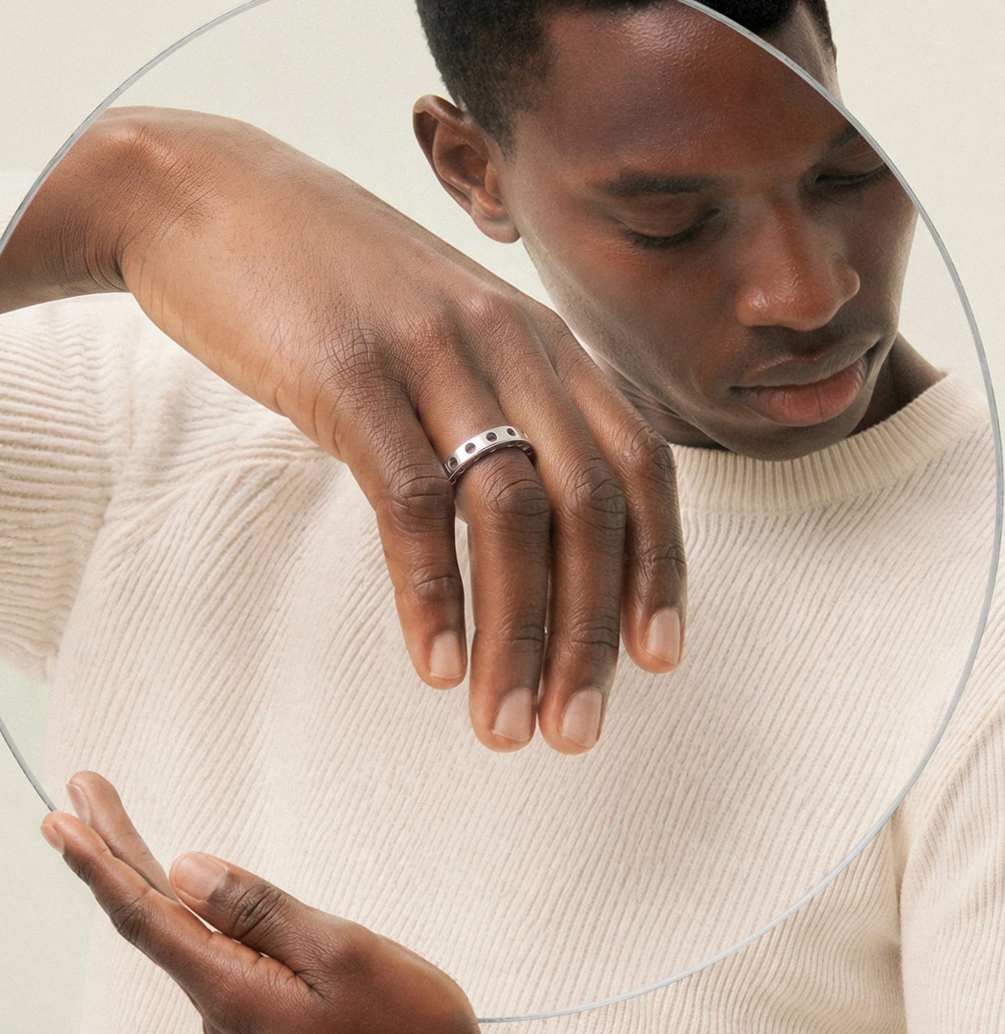 Man wears ring behind magnifying glass.