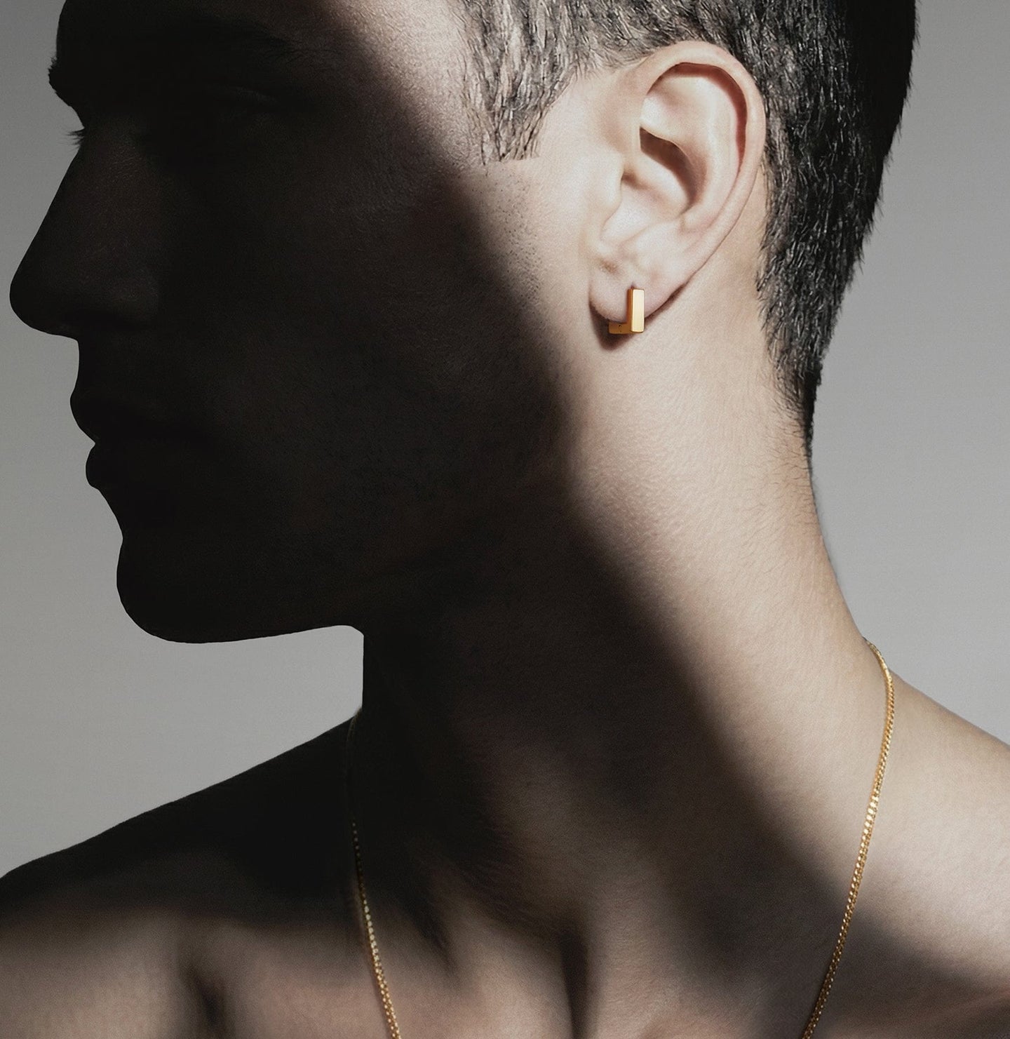 Man wearing earring and cuban chain necklace.