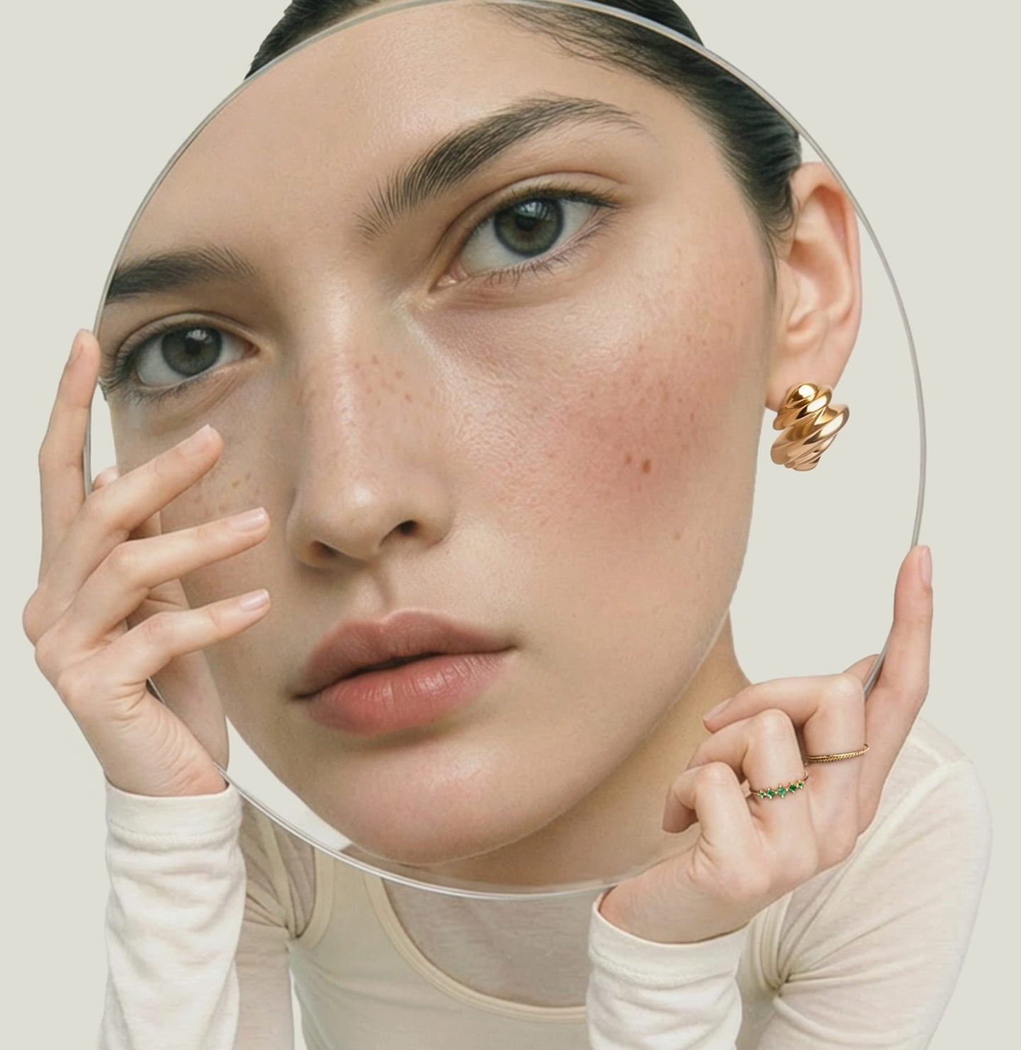 woman wears earring behind magnifying glass
