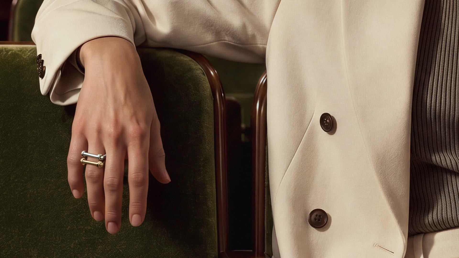Miansai stacked rings worn on a hand with slim bands and bar details against a cream blazer