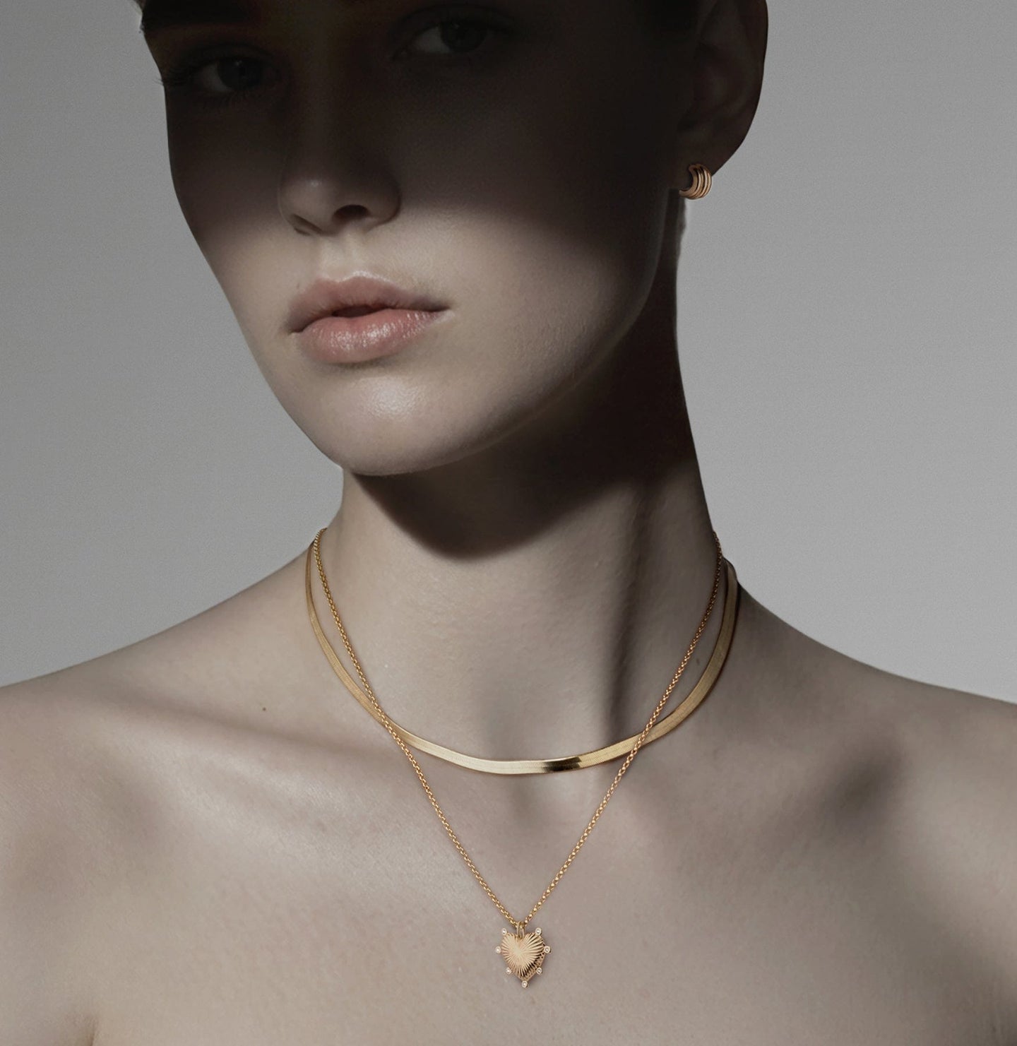 Woman wearing earring and two necklaces.