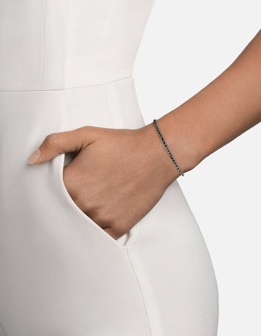 Miansai 2mm braided chain bracelet in sterling silver with black nylon cord woven through polished links worn on the wrist