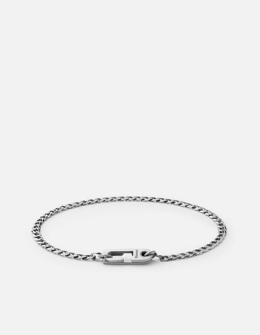 Miansai Annex Cuban curb chain bracelet in oxidized sterling silver laid flat with polished integrated clasp visible