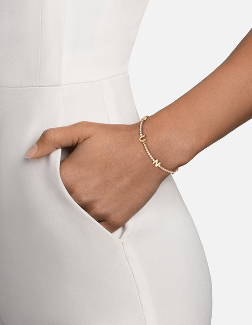 Miansai Signature tennis bracelet in polished 14k yellow gold with pavé diamonds and raised letter detail worn on the wrist