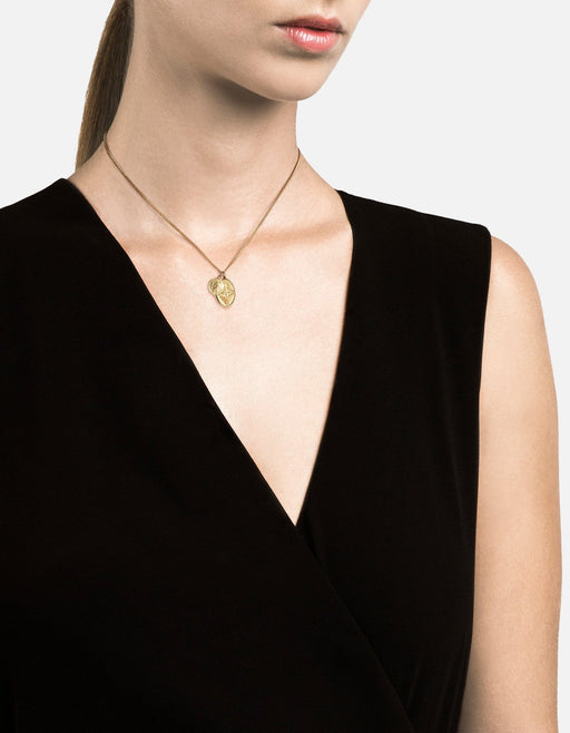 Miansai Mini Dove pendant necklace in gold vermeil worn at the neck with layered dove and Saint Christopher medallions on a fine chain