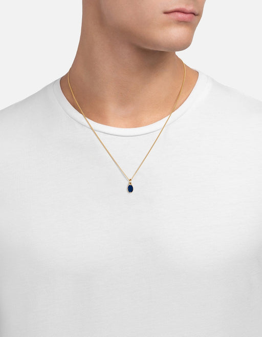 Miansai Portal pendant necklace in gold vermeil with a small blue enamel porthole pendant layered at the neck over a white shirt