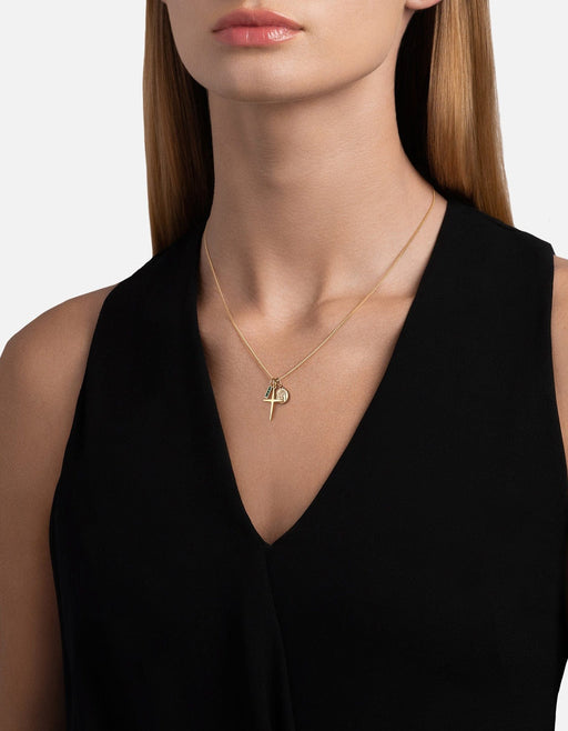 Miansai gold vermeil Aegis Trilogy cross necklace with green agate and symbolic charms worn at the neck over a black V neck top