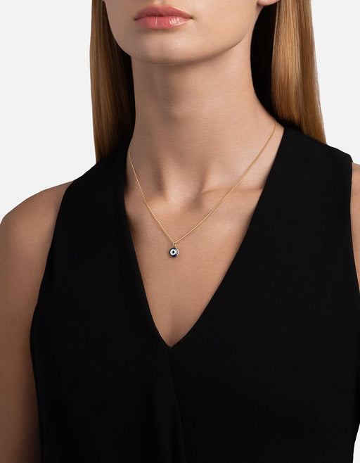 Miansai Ojos pendant necklace in gold vermeil with a blue enamel evil eye worn at the neck over a black V-neck top