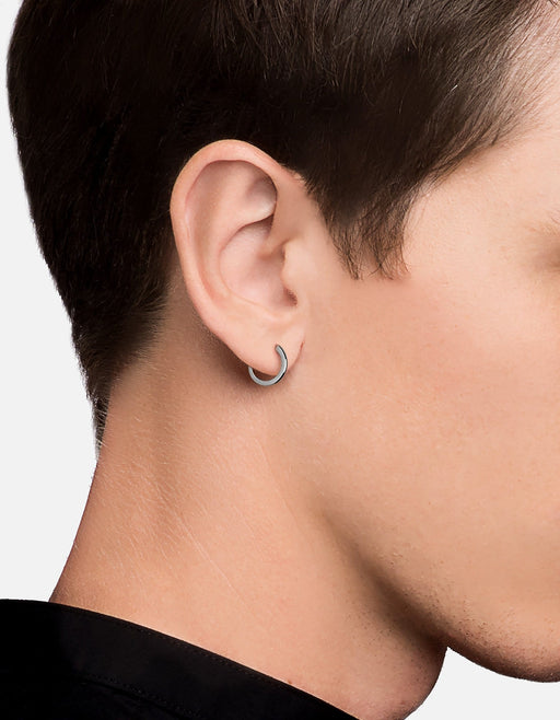 Miansai Aeri huggie earring in polished sterling silver worn on the ear with a curved architectural hoop design