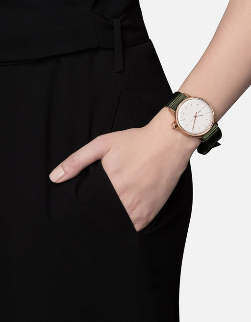 Miansai M12 Swiss watch with a rose tone stainless steel case white dial and hunter green climbing webbing strap worn on the wrist