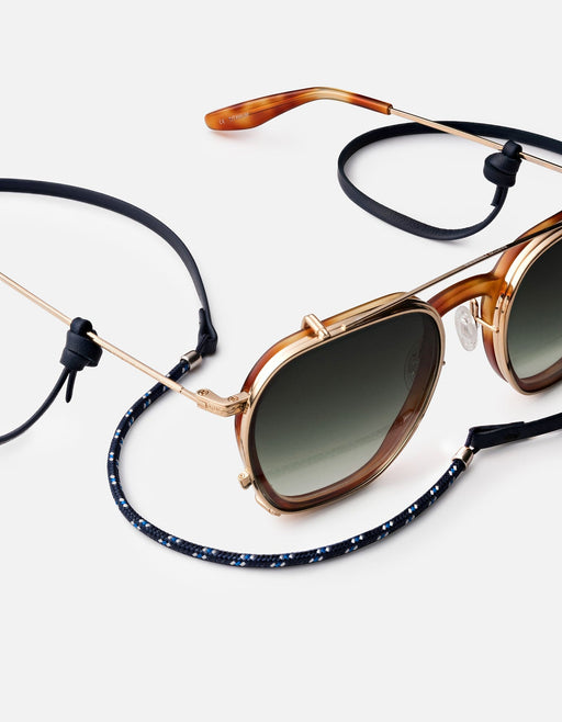 Miansai Nexus sunglass cord in black Italian leather and navy nylon rope with sterling silver finishes attached to brown sunglasses